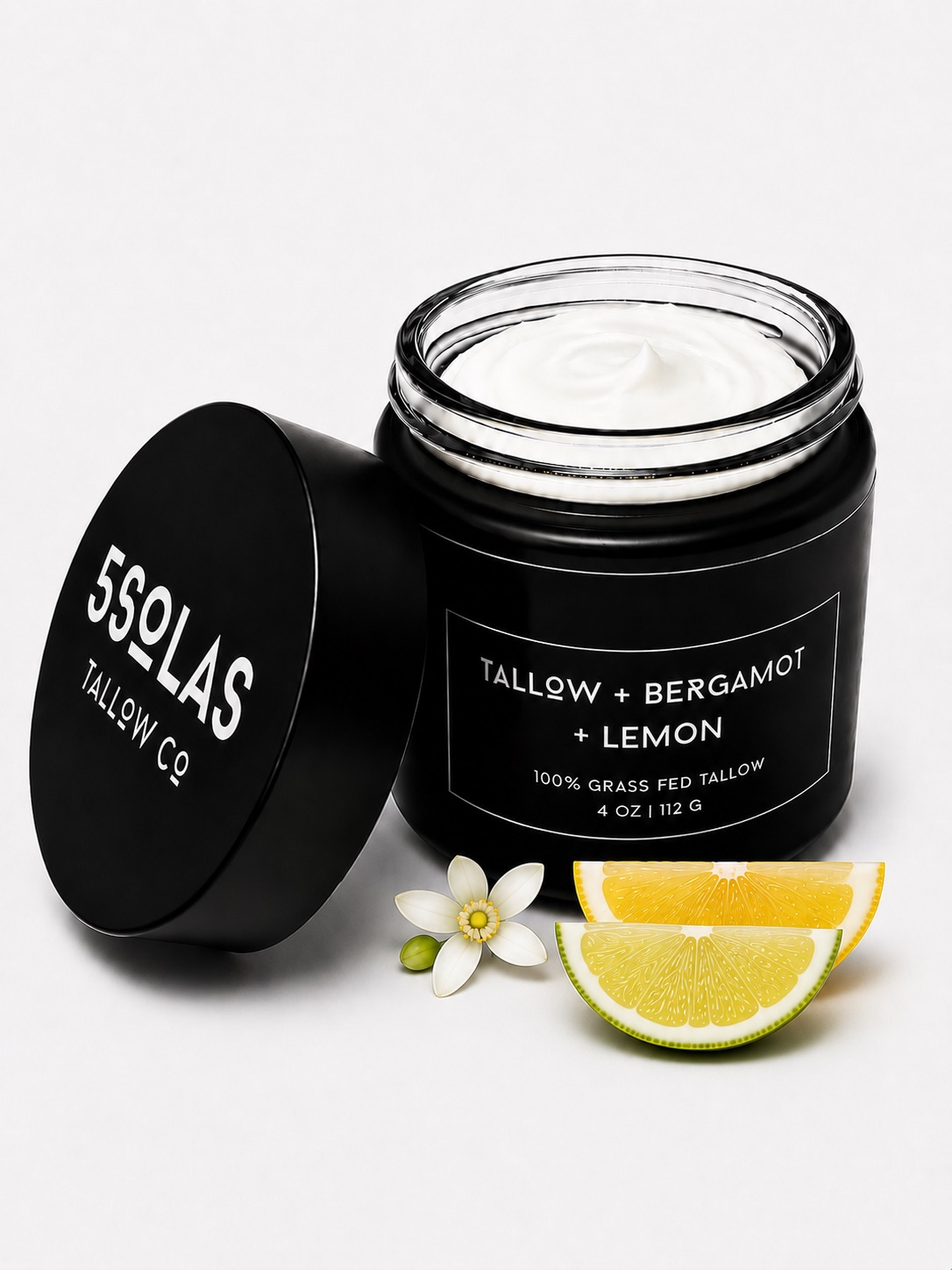 Open jar of 5Solas Tallow Co. grass‑fed tallow skin balm in the bergamot + lemon blend, shown with natural ingredients around the container.