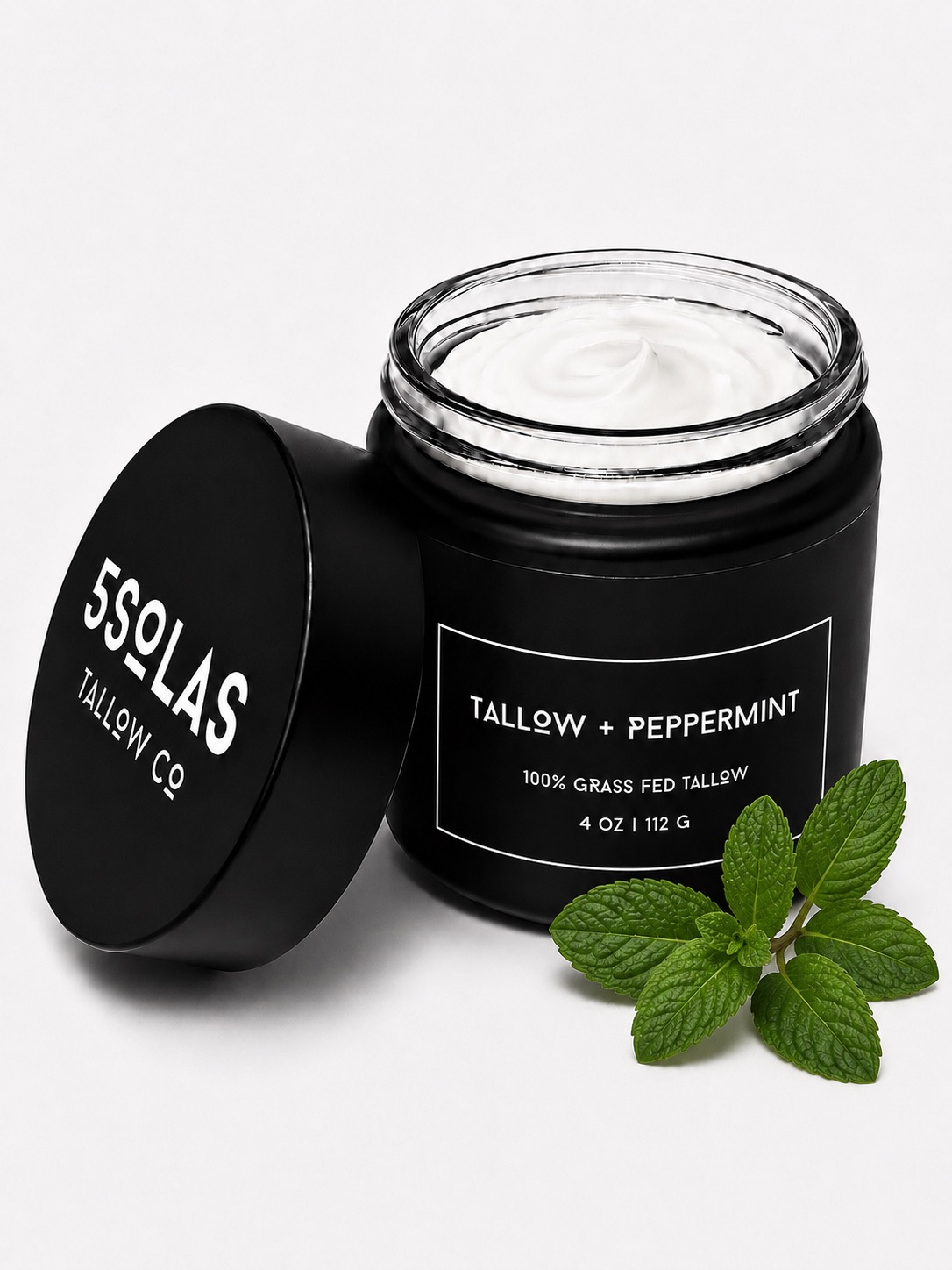 Open jar of 5Solas Tallow Co. grass‑fed tallow skin balm in the peppermint blend, shown with natural ingredients around the container.